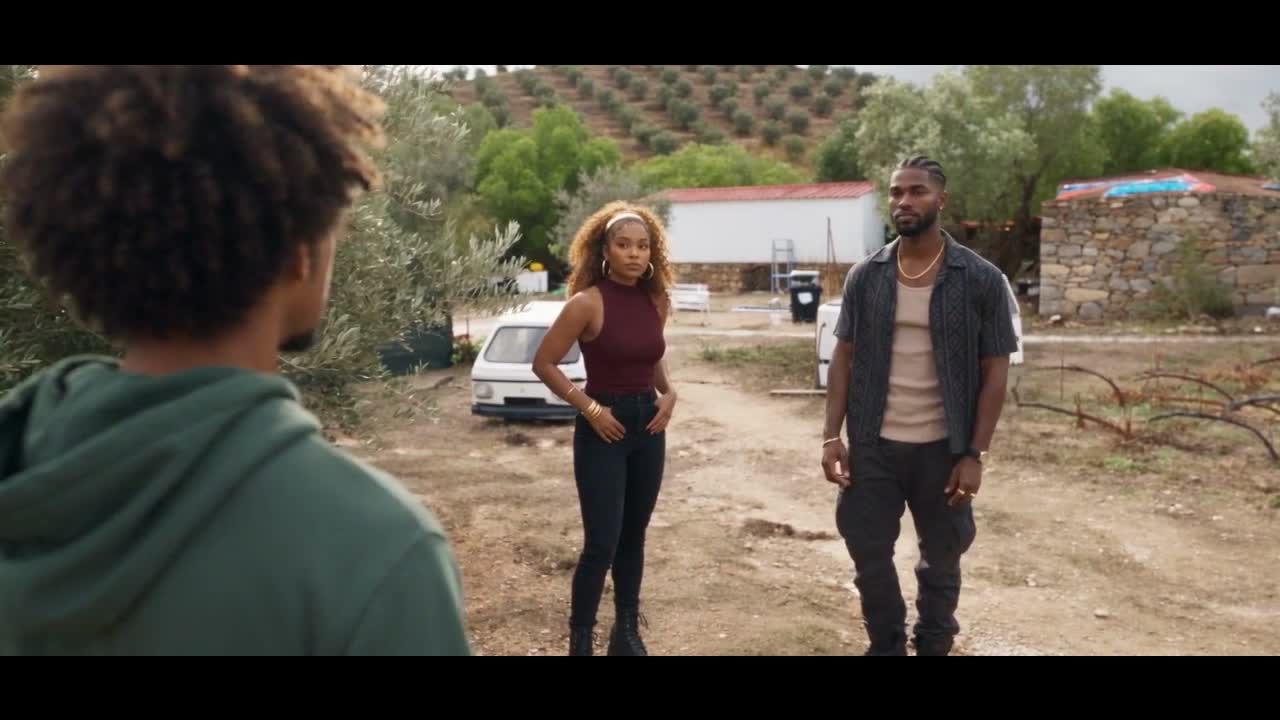 Concept render: Daniel from behind in a green hoodie facing Amara Sol and Kai Zuri at the clearing, caravans and olive groves behind them